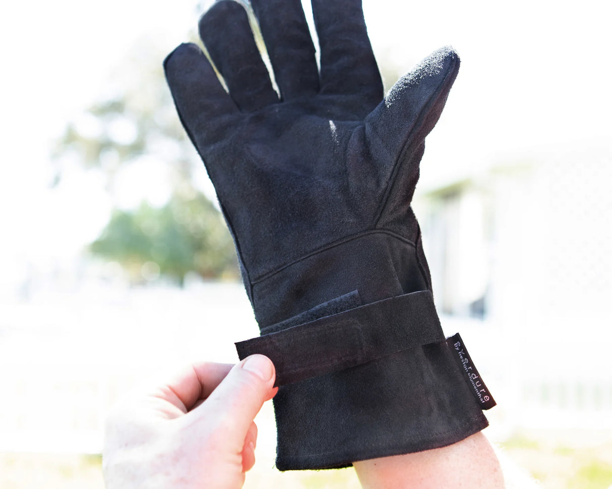 Black glove held by a hand with a blurred natural background