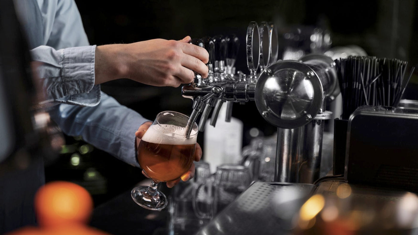Bartender pouring a glass of beer from a tap at a bar.