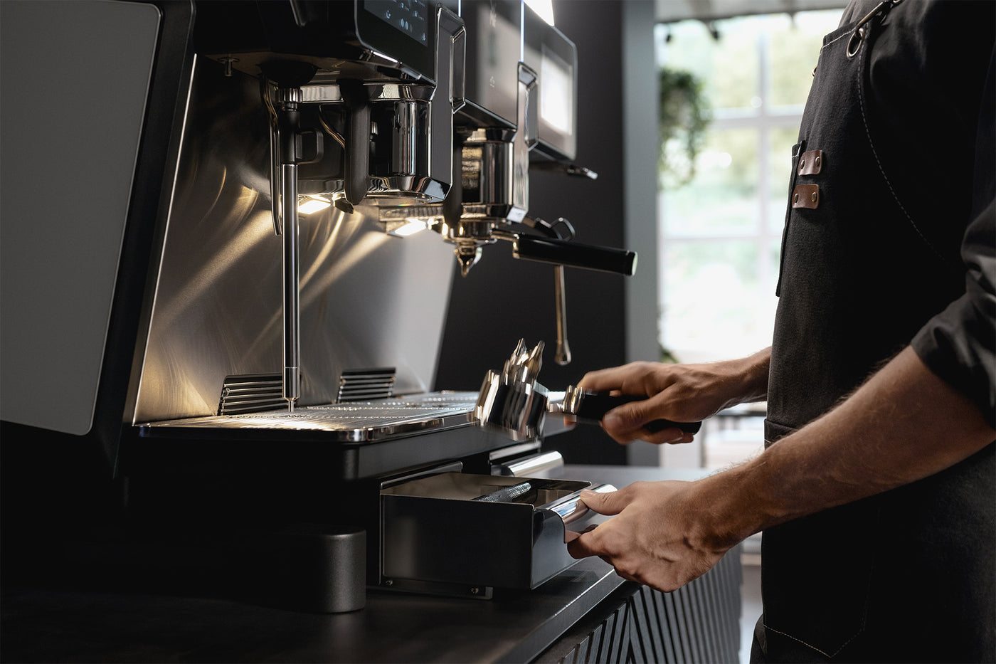 Person operating a coffee machine in a kitchen setting