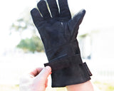 Black glove held by a hand with a blurred natural background